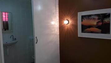 Un baño con lavamanos, espejo y un cuadro enmarcado de un atardecer.