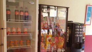 A vending machine with snacks and drinks, a refrigerator stocked with beverages, and a trash bin. - Hotel Du Centre (Saint-Denis)