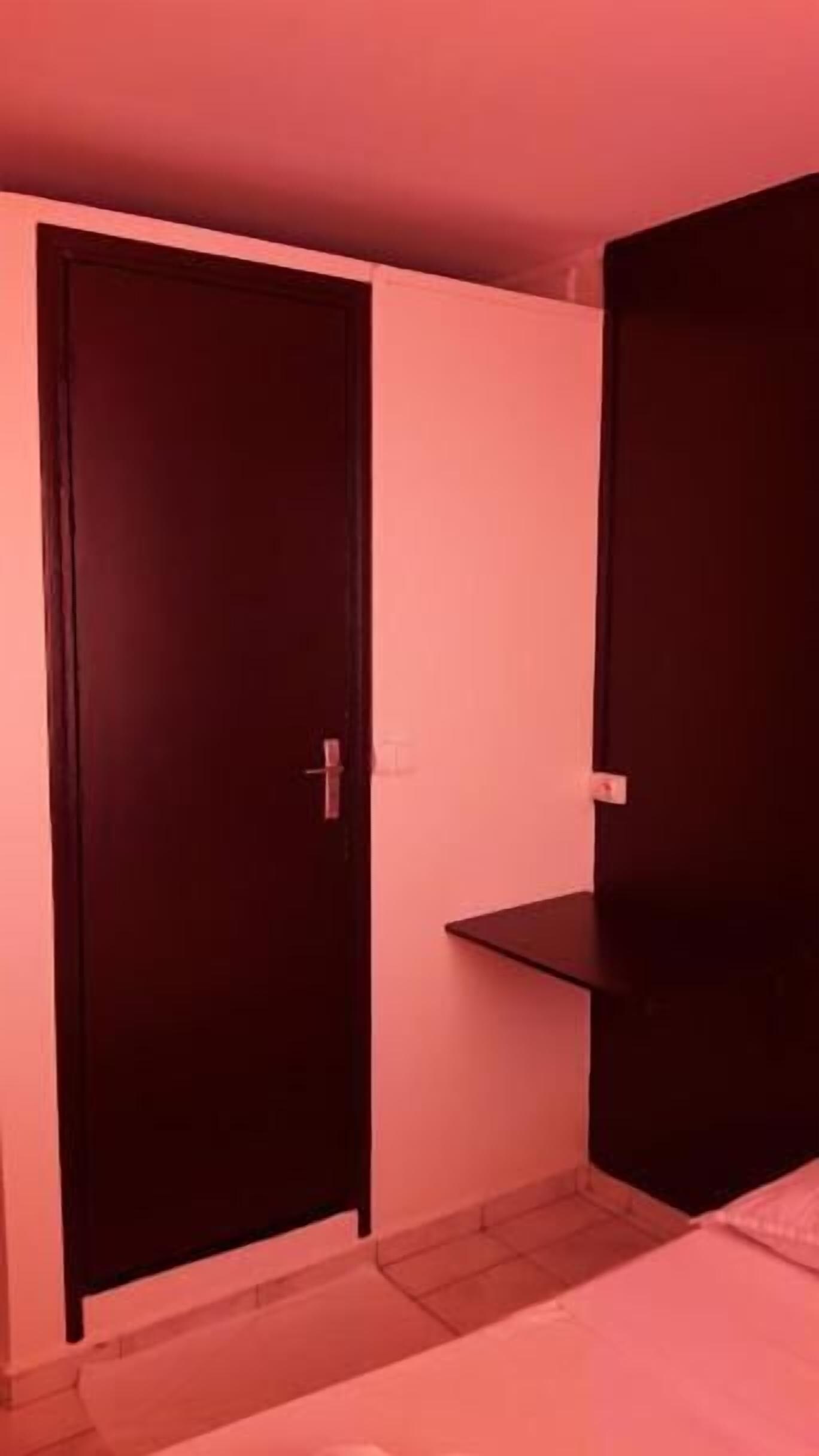 A room with a dark-colored wardrobe and a small shelf unit against the wall.