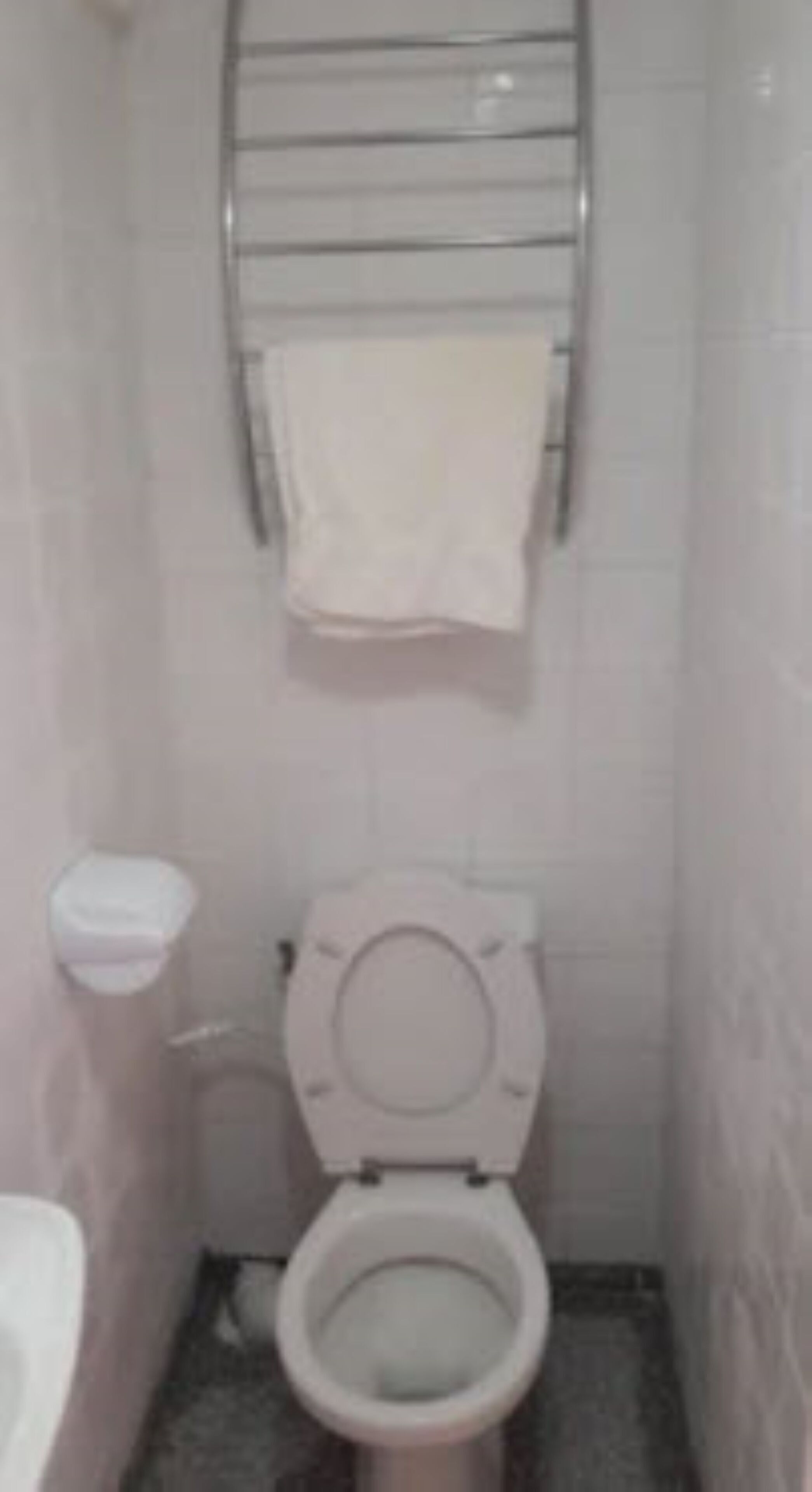 Un baño pequeño con inodoro, lavamanos y toallero.