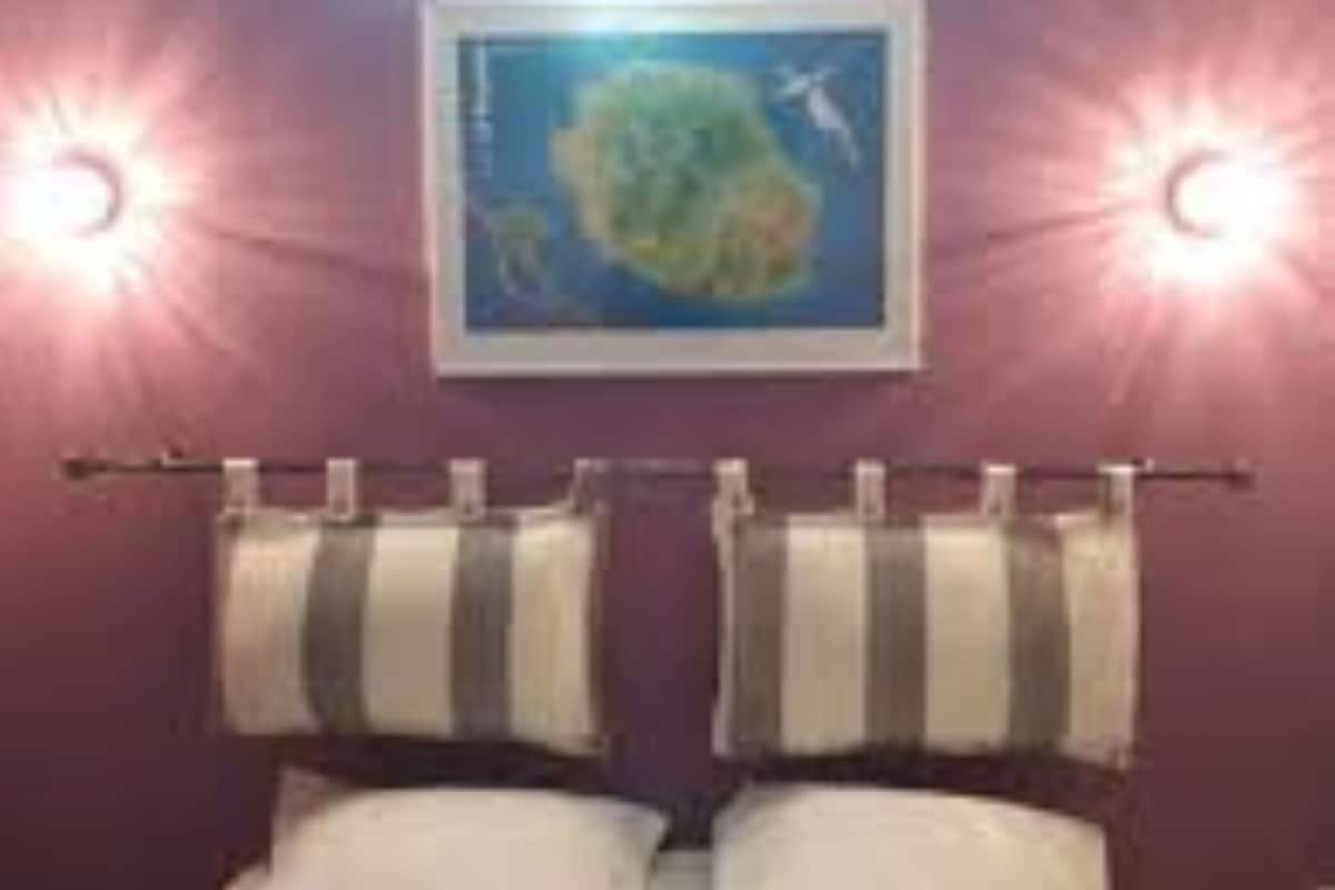 A bedroom with a bed, two towels hanging on a rack, and a wall-mounted picture.