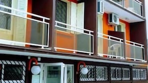 A multi-story building with balconies, air conditioning units, and potted plants. - Hotel Du Centre (Saint-Denis)