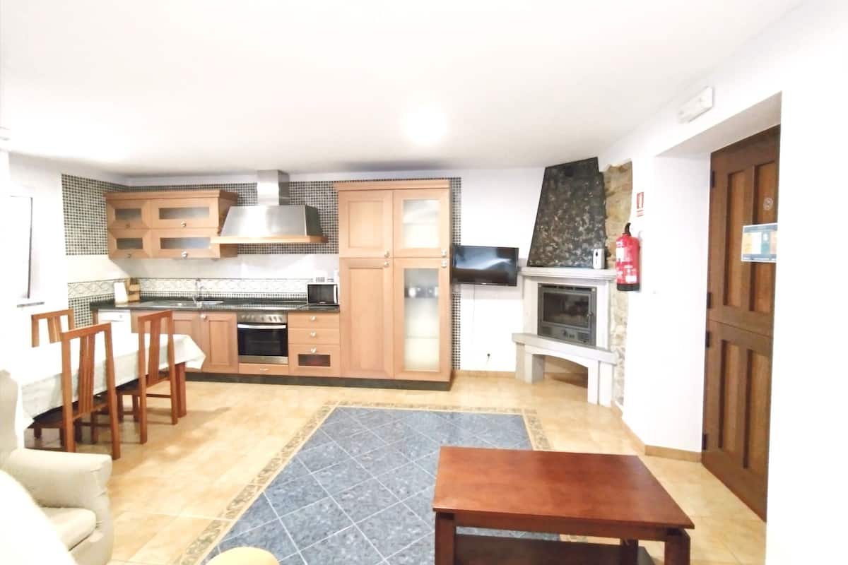Cocina compacta con armarios de madera, horno empotrado y microondas.
