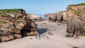 Una zona costera con acantilados rocosos y una playa arenosa.