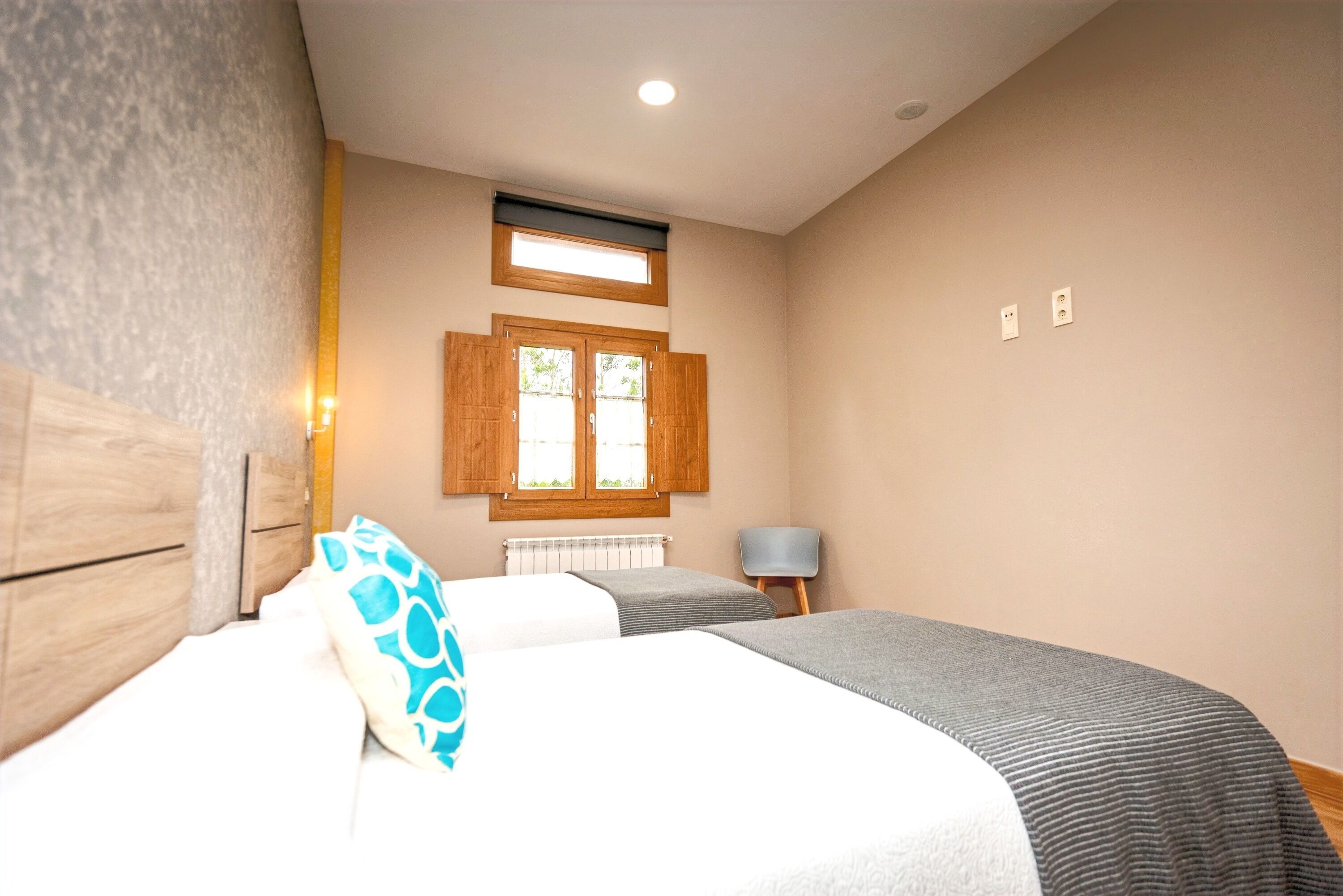 A bedroom with a bed, a window with shutters, a radiator, and a chair.