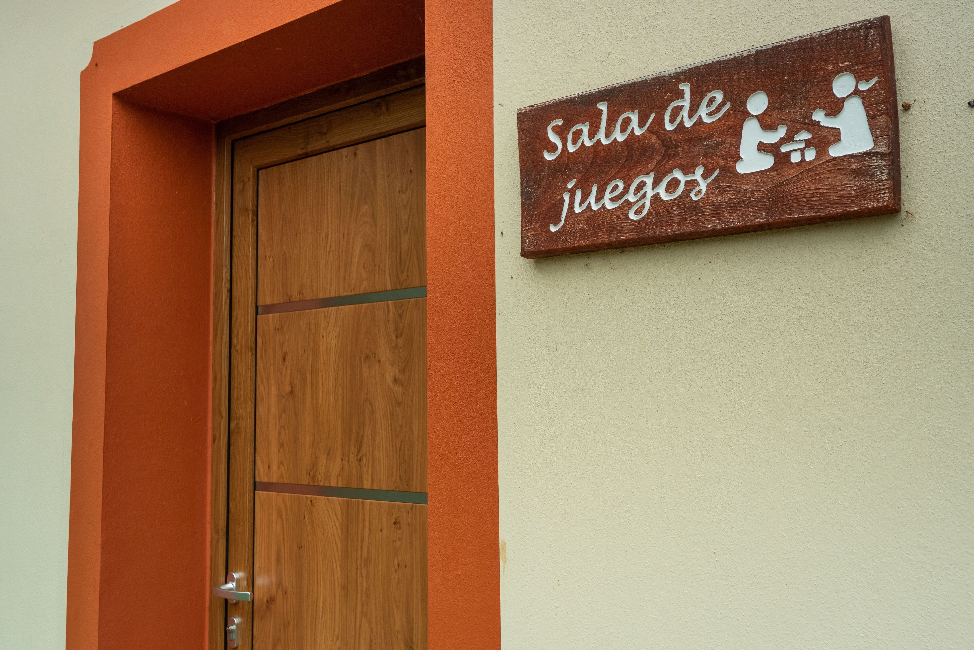 Una puerta de madera con un letrero encima que dice 'Sala de juegos'.