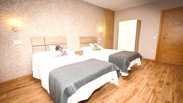 Een hotelkamer met twee bedden, houten vloeren en een grote kledingkast.