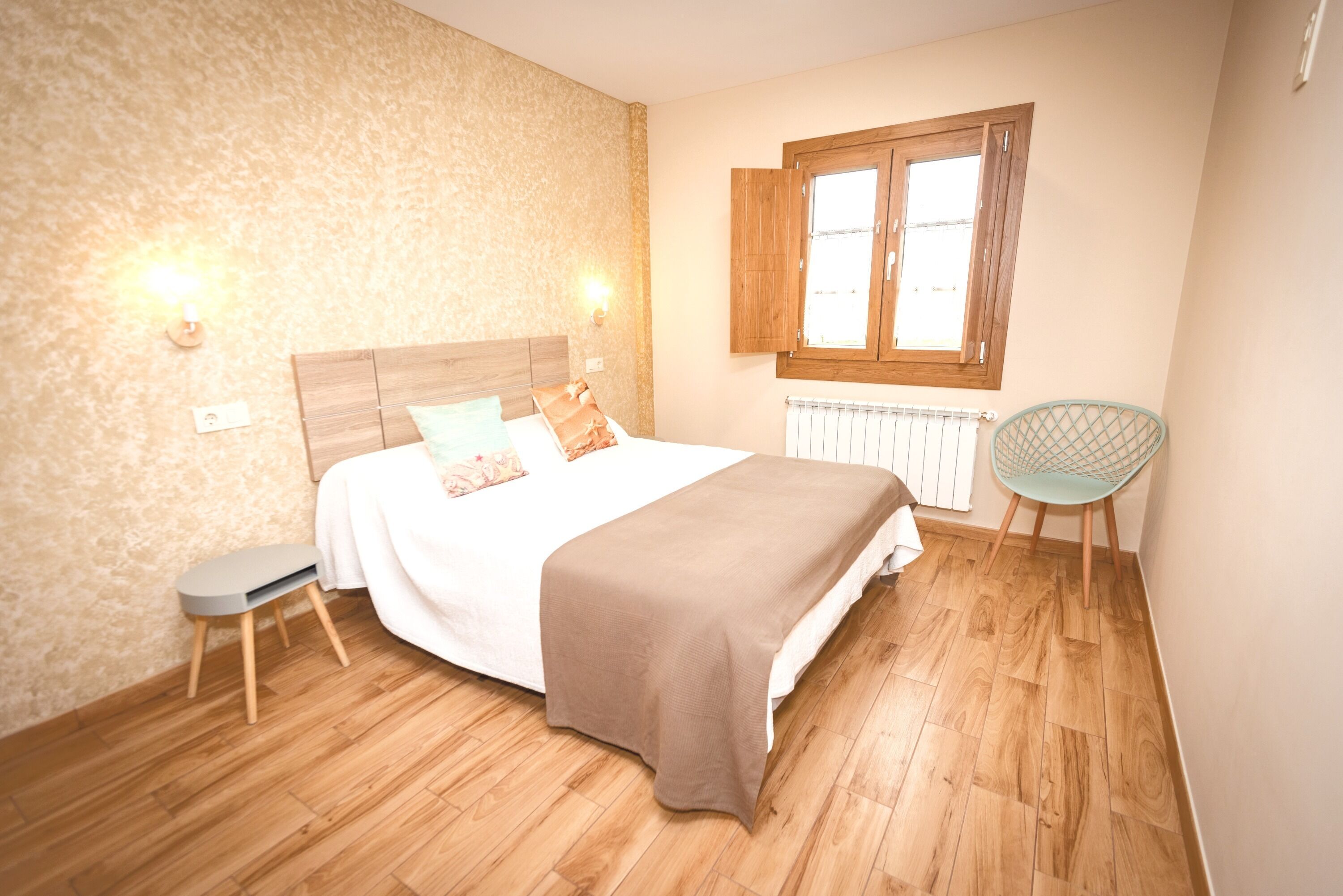Una camera da letto con un letto di legno, un comodino, una sedia e una finestra con persiane in legno.