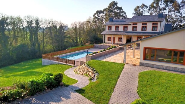 Una casa grande con piscina, senderos pavimentados y césped cuidado.