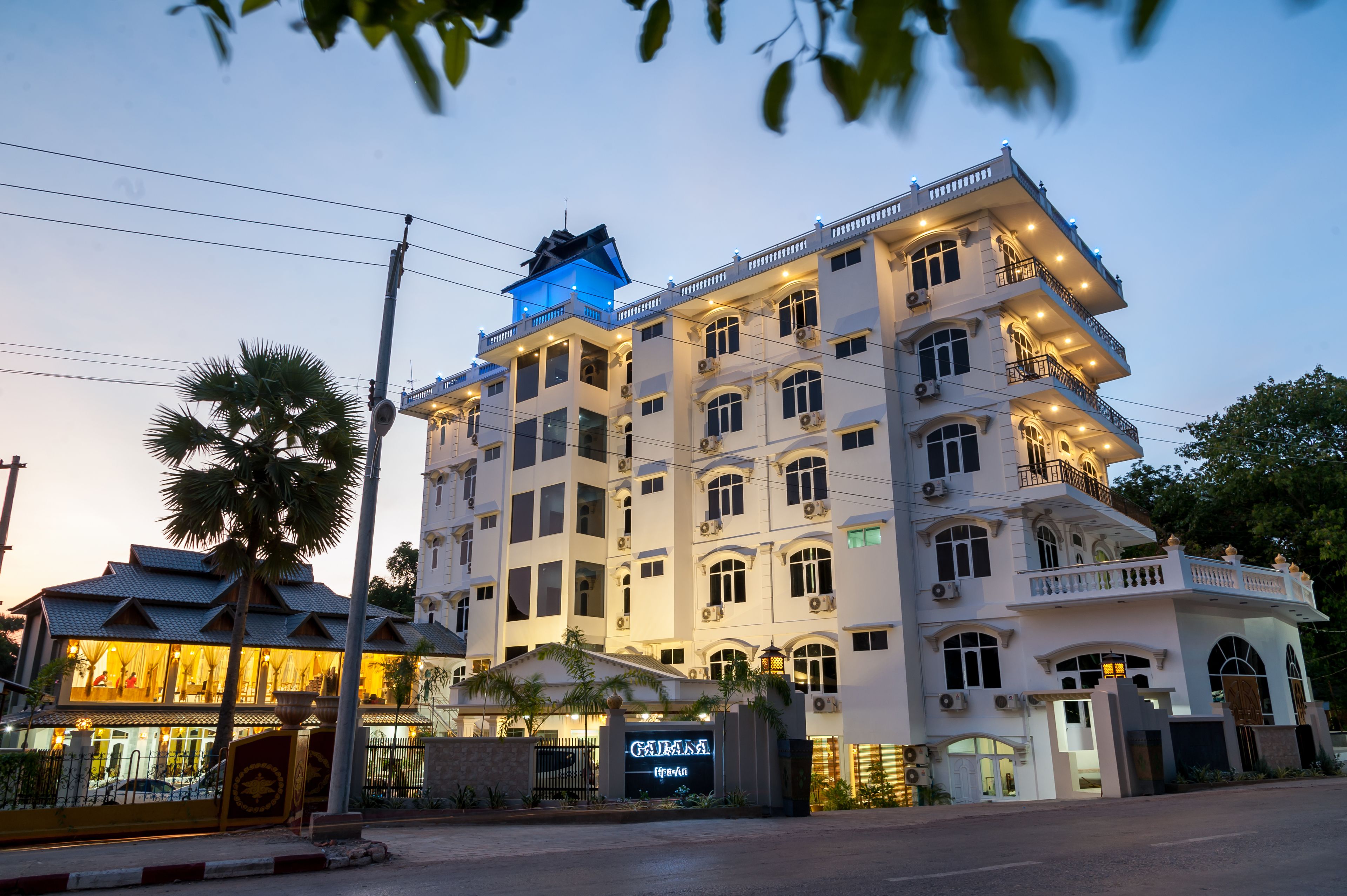 A multi-story hotel with a prominent entrance, a blue-lit tower, and a well-lit facade.