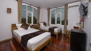 Habitación de hotel con dos camas, televisión, refrigerador y ventanas grandes.