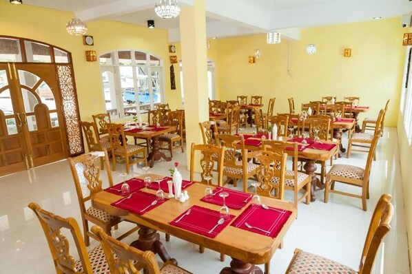Un comedor con varias mesas y sillas, dispuesto en un ambiente amplio.