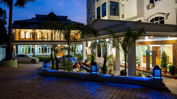 Un hotel de estilo arquitectónico tradicional, con una entrada bien iluminada y un camino de entrada pavimentado.