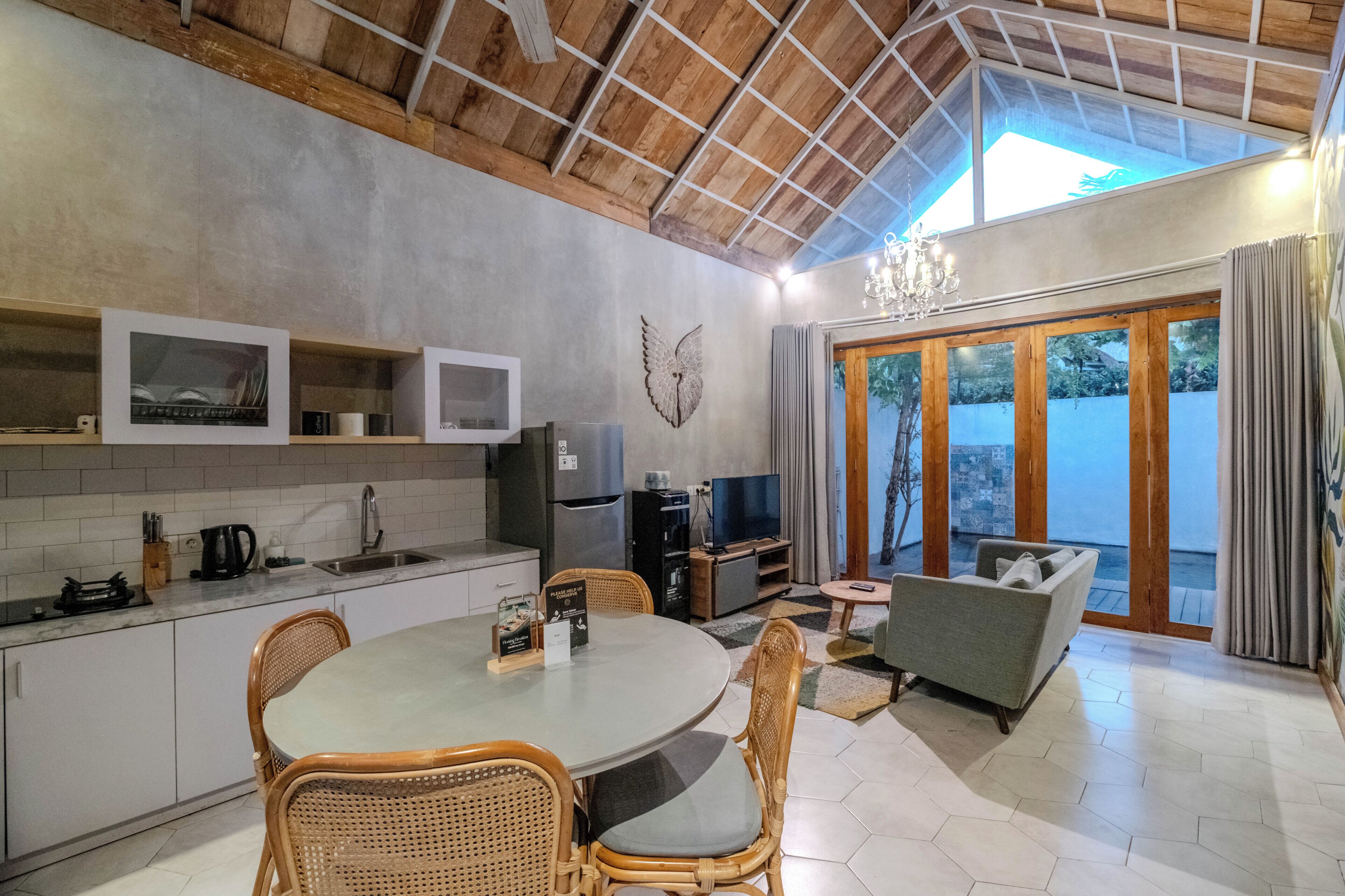 A modern kitchen with a dining area, wooden ceiling, and large windows.