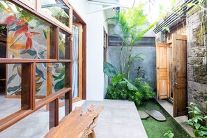 A modern interior with a wooden bench, glass doors, and tropical plants.