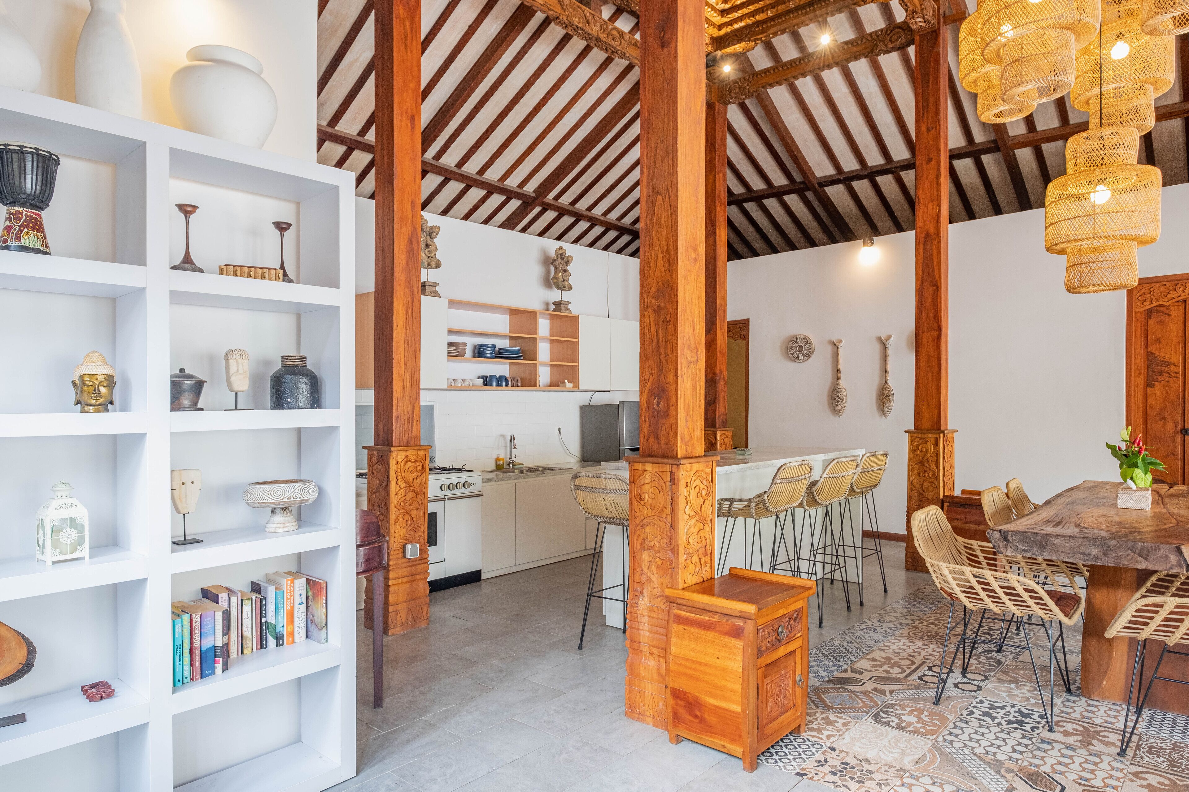 A spacious kitchen with white cabinets, a wooden dining table, and a patterned rug.