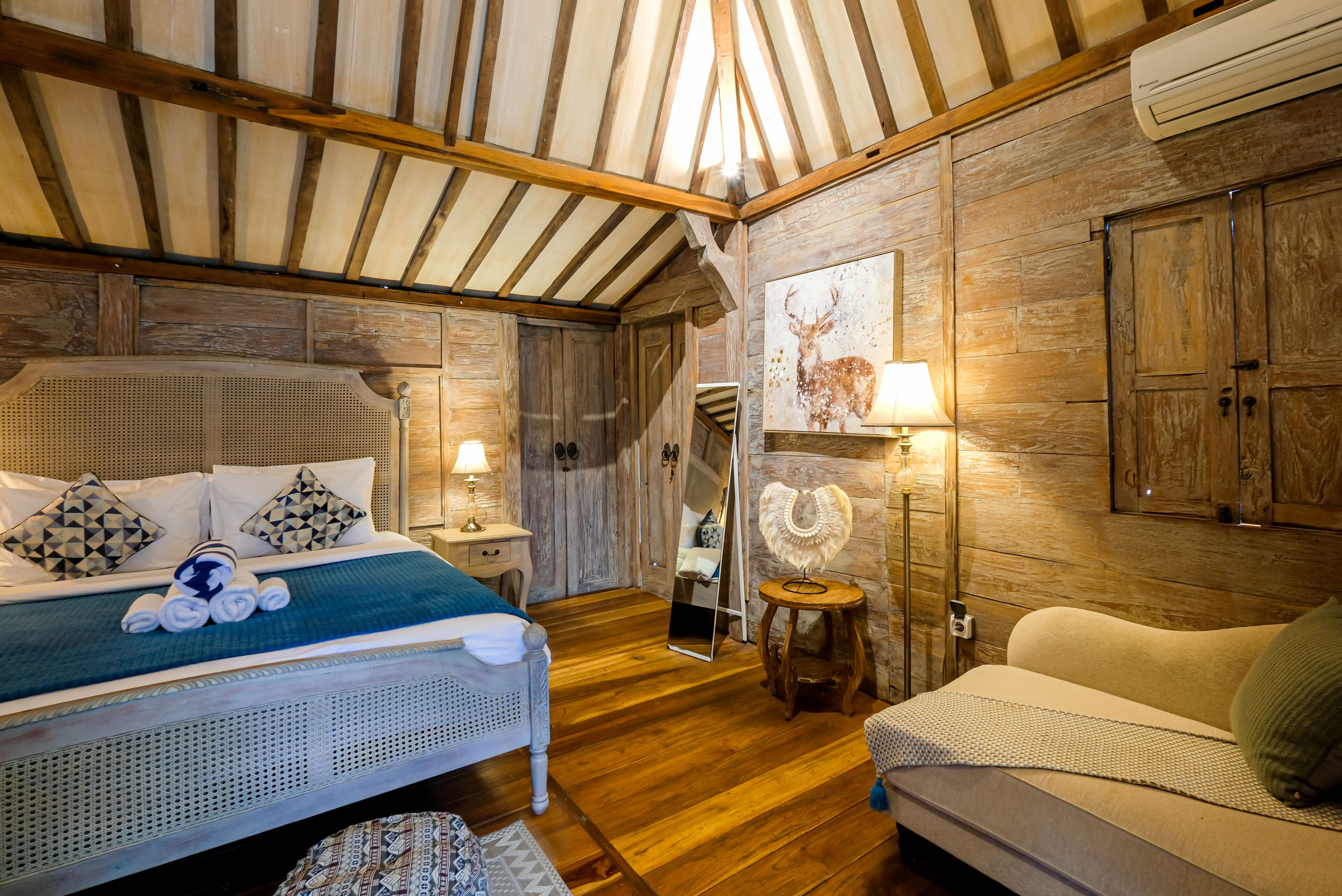 Une pièce confortable avec un lit, un canapé, des murs en bois et un miroir.