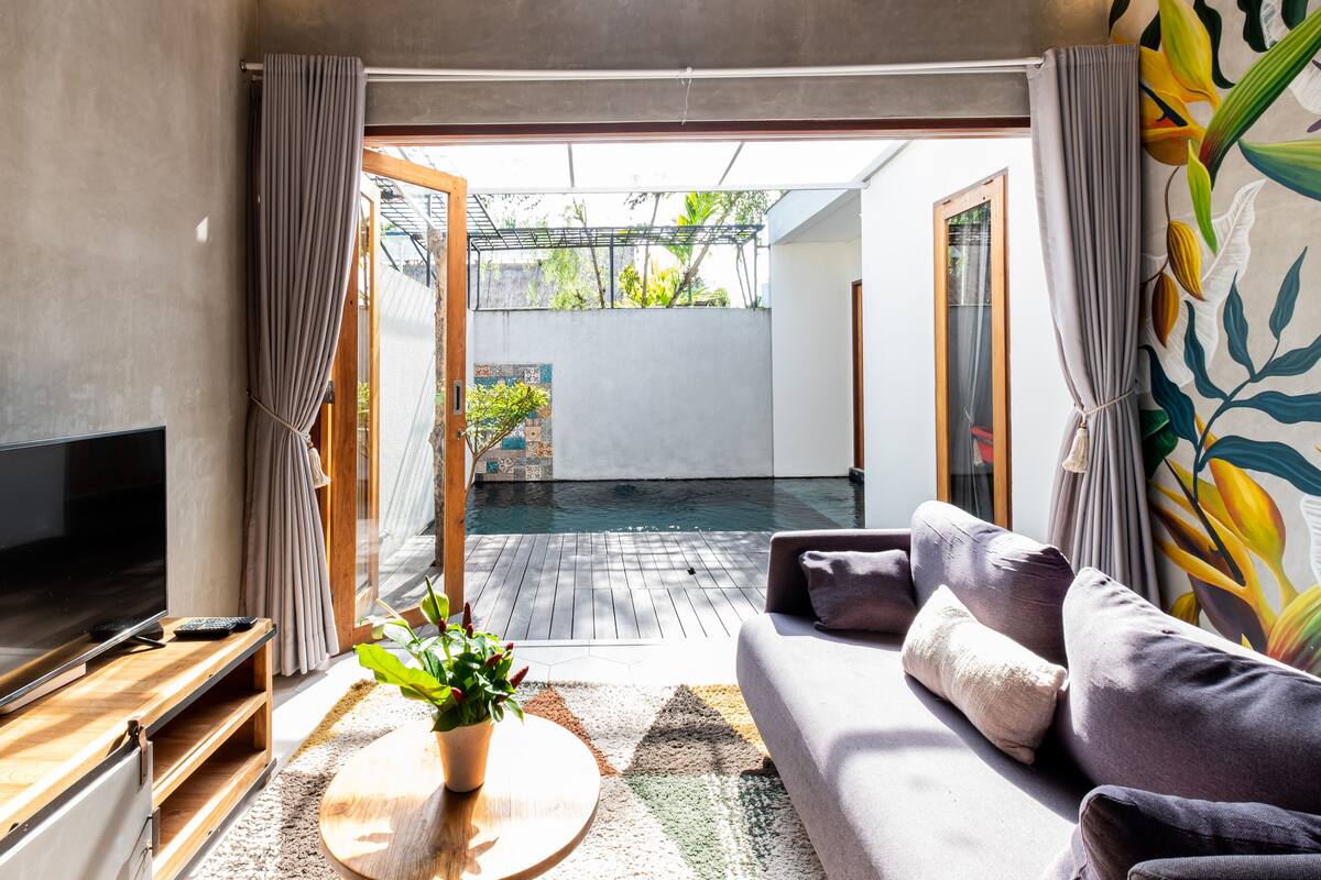 A modern living room with a TV, sofa, and a small table with a plant.