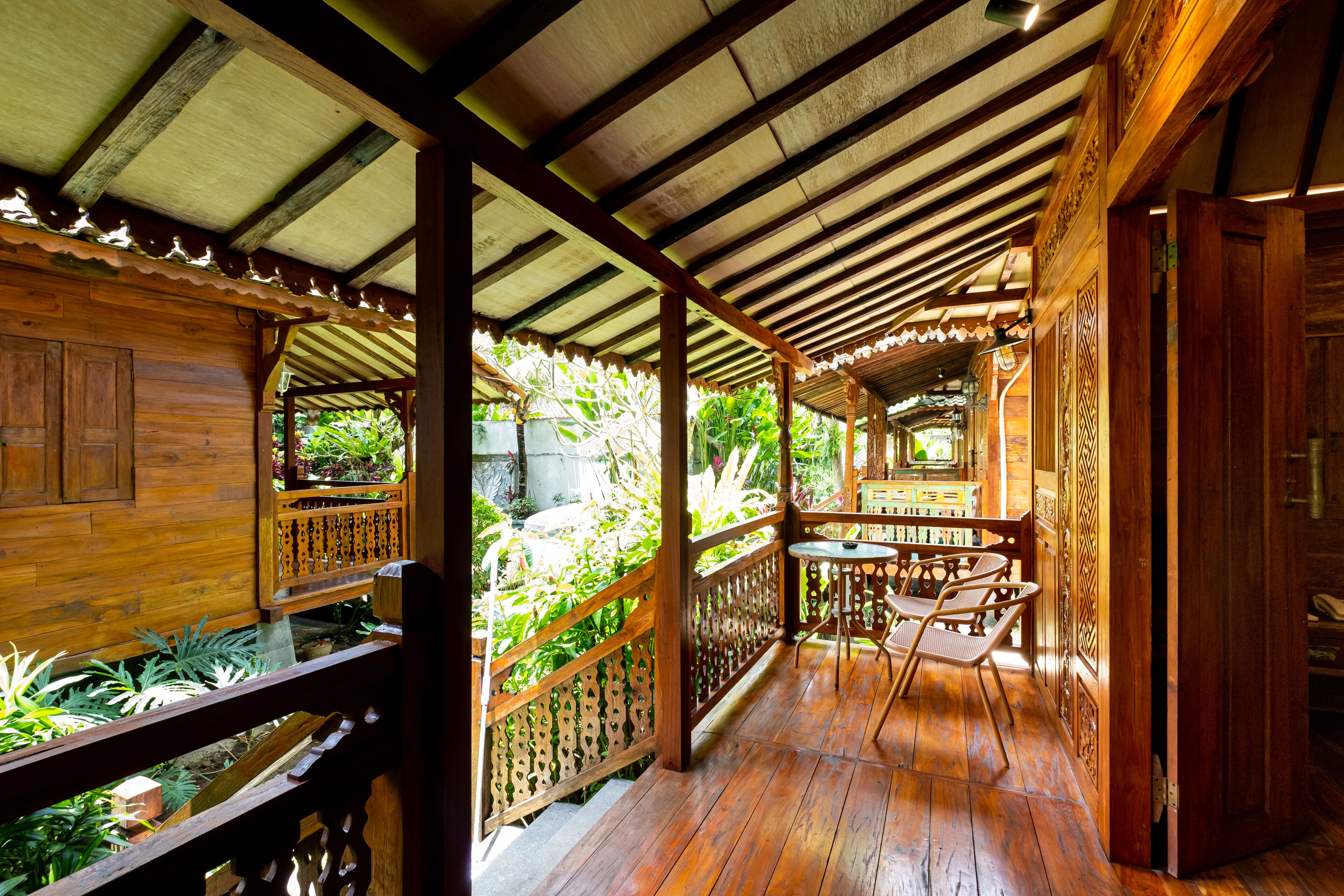 A wooden veranda with a wooden railing, a small table, and chairs.