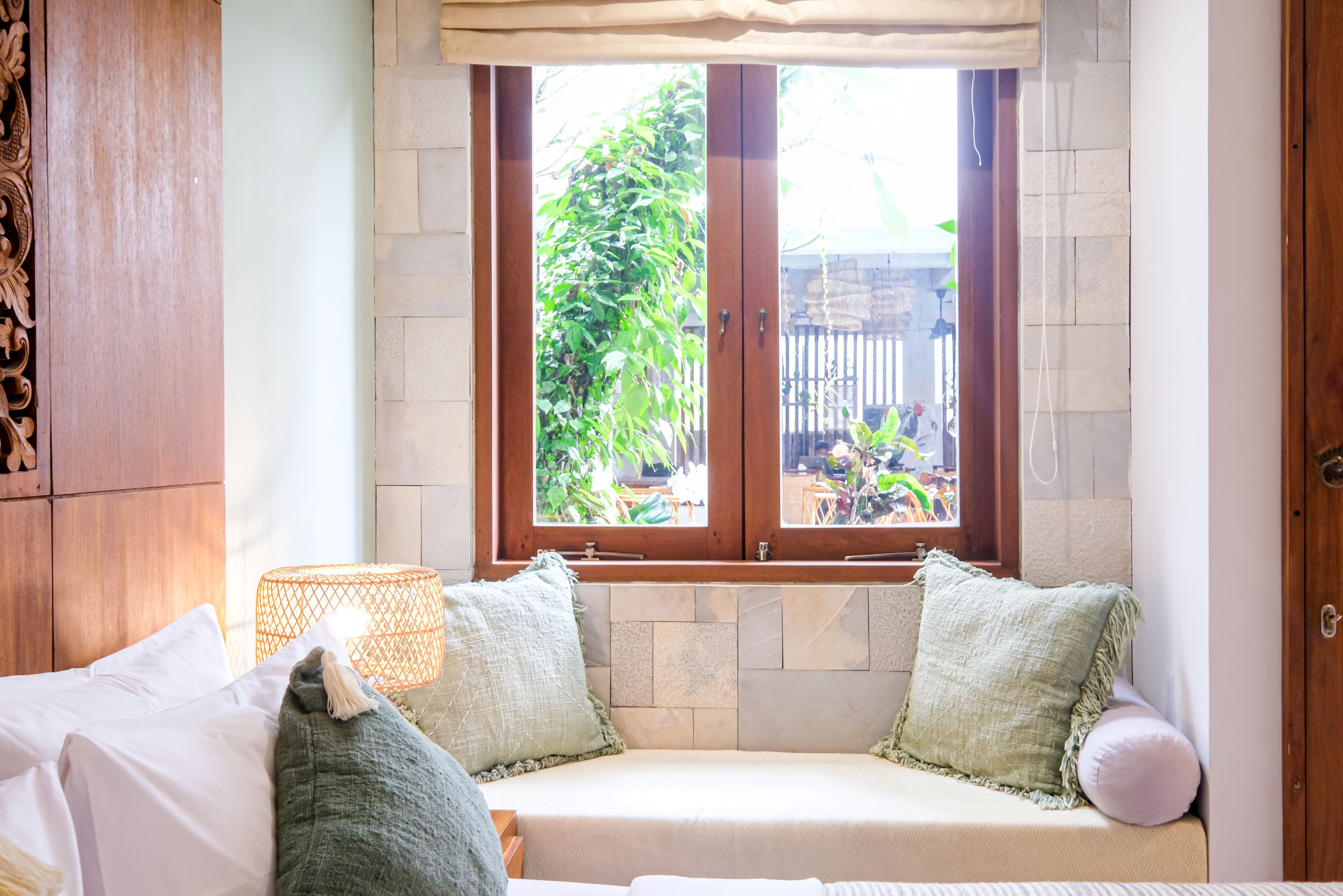 A cozy room with a built-in bench, a window with a view of the garden, and a wooden door.