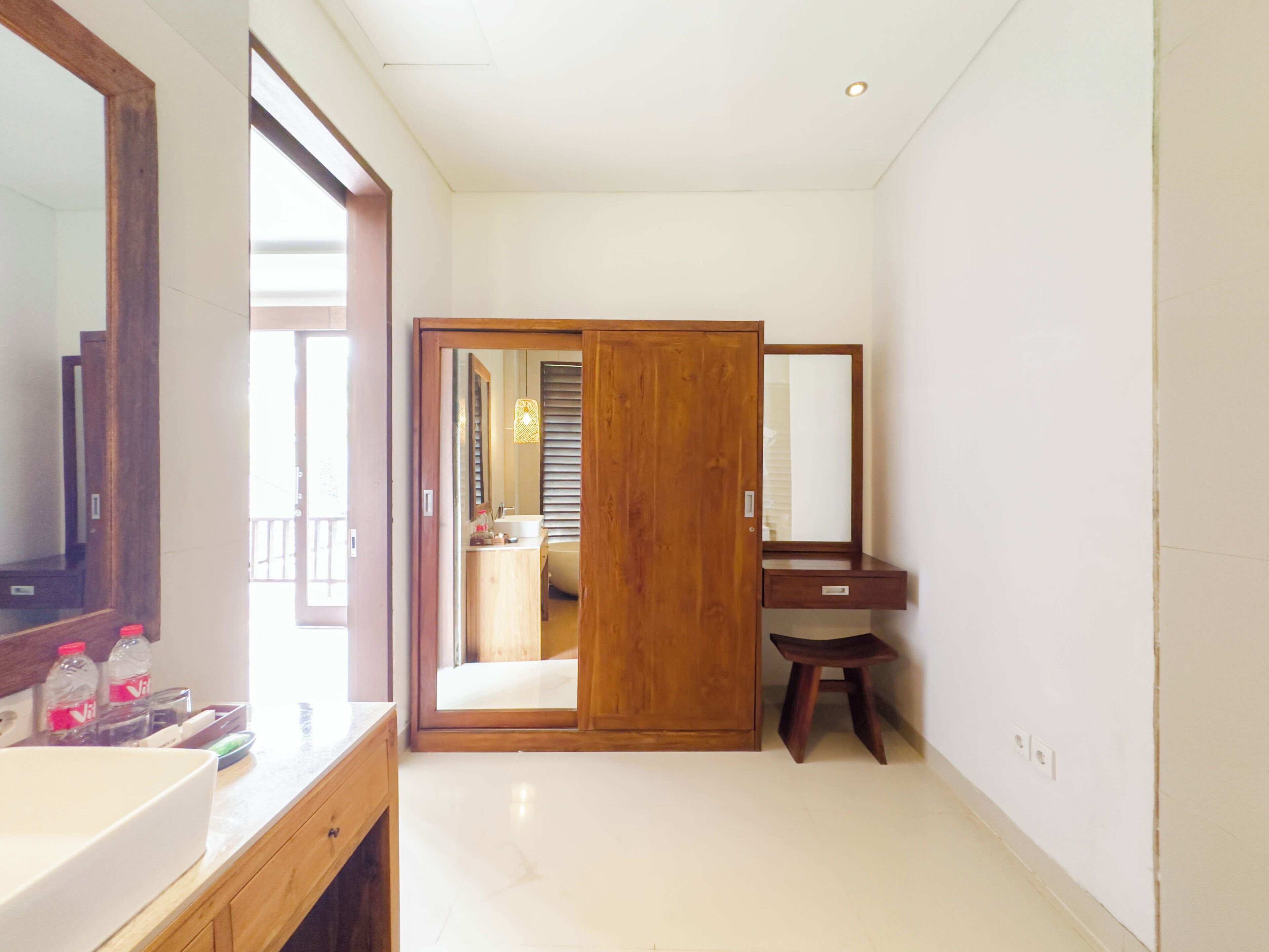 Un baño con tocador de madera, un espejo grande y una puerta corredera que da a la zona de ducha.