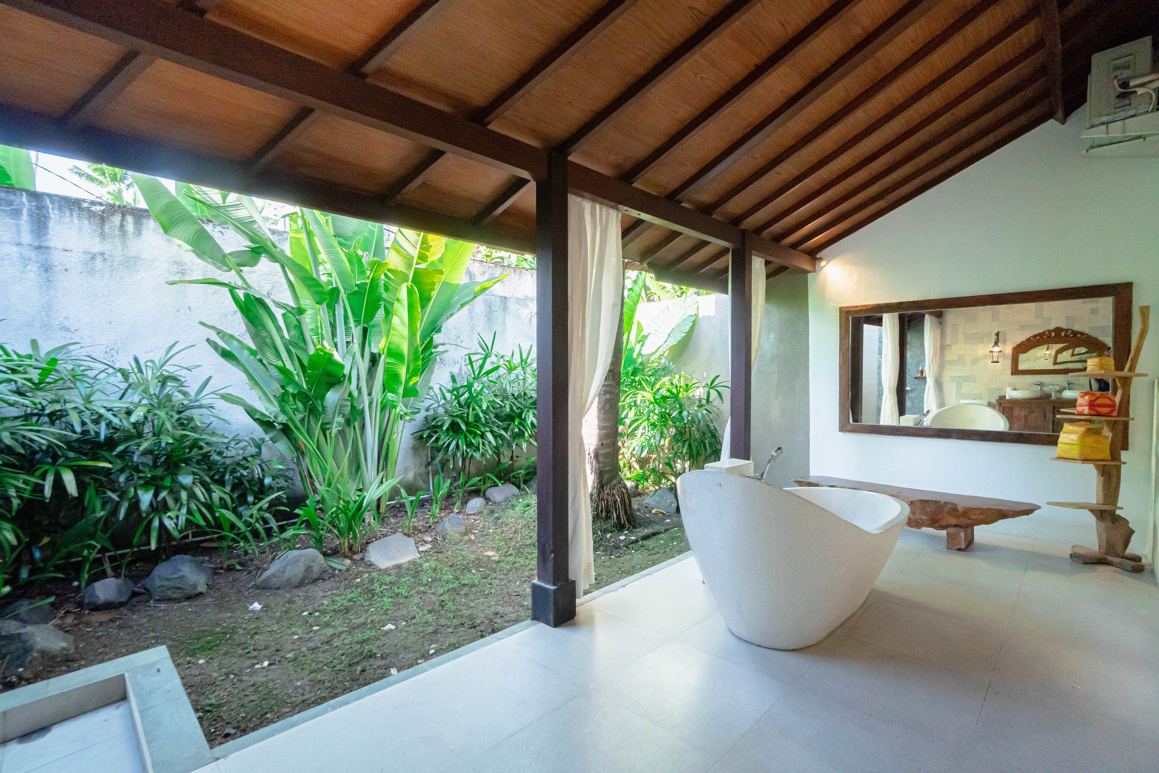 A modern interior with a large white bowl, a wooden bench, and a mirror on the wall.