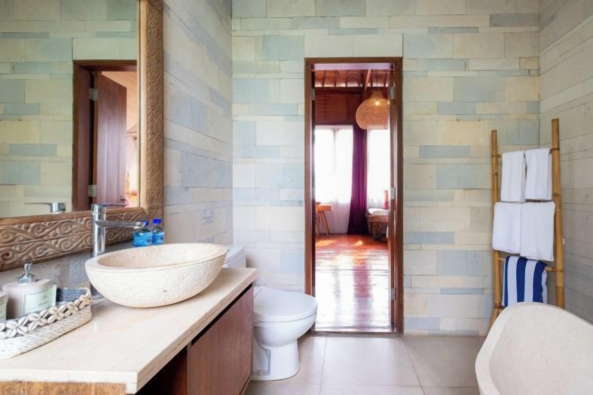 A bathroom with a large vessel sink, a toilet, and a shower area.