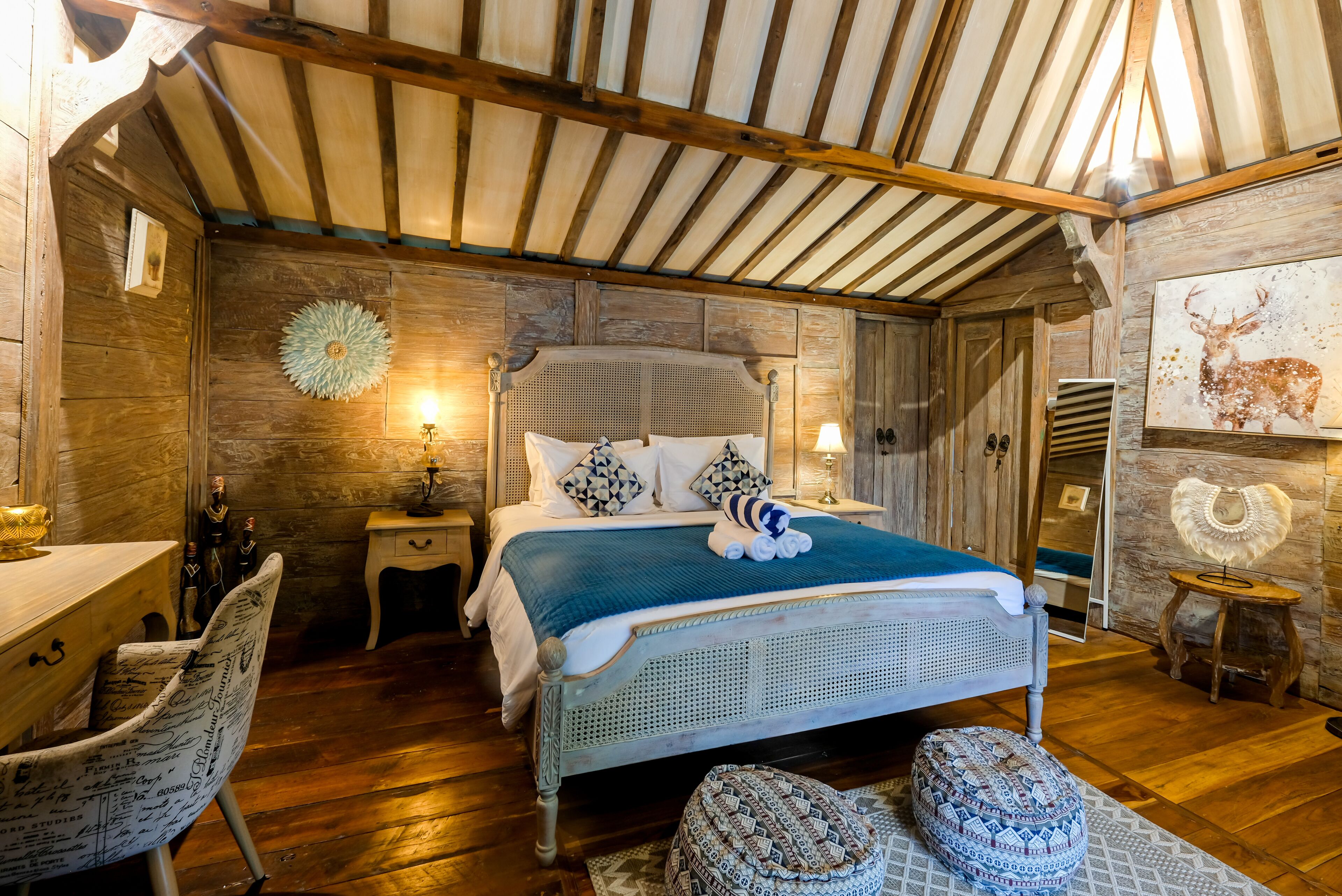 A rustic wooden bedroom with a bed, bedside tables, a chair, and a wall-mounted artwork.