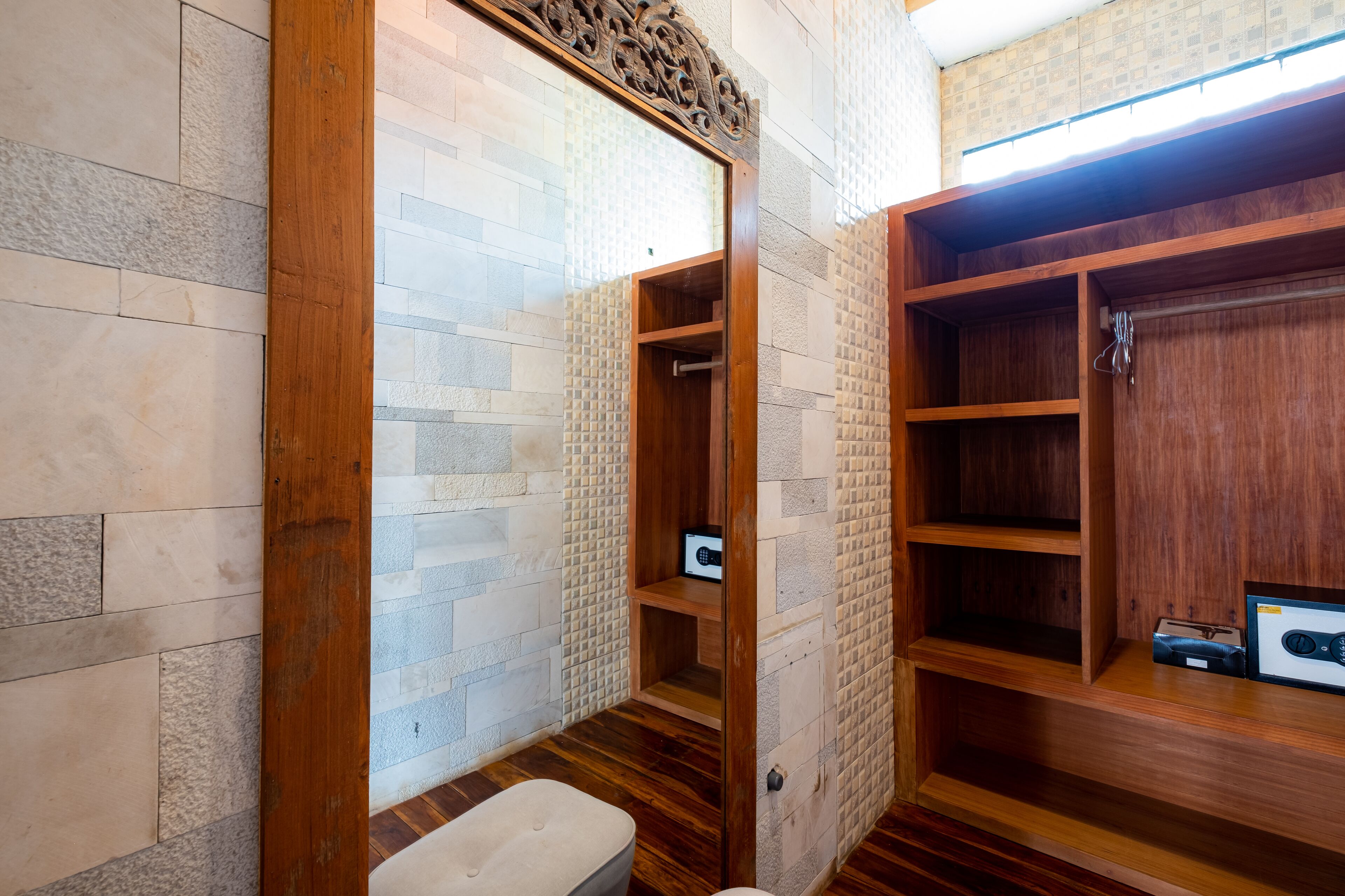 Een badkamer met een houten wastafelmeubel, een spiegel en een betegelde muur.