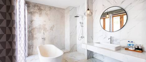 A modern bathroom with a freestanding bathtub, a large mirror, and a shower area.