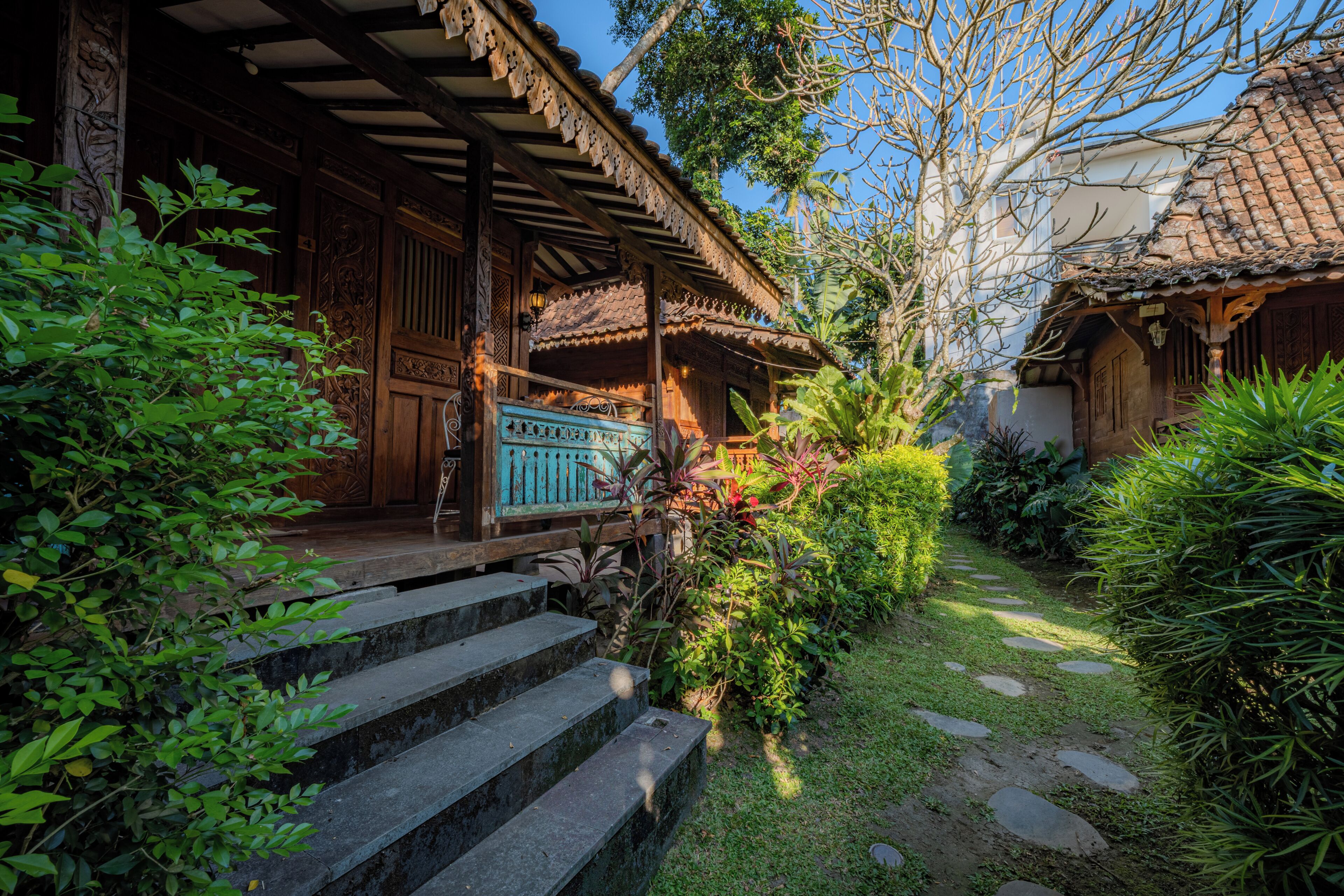 Una casa in legno tradizionale con veranda, scalini in pietra e rigogliosa vegetazione.