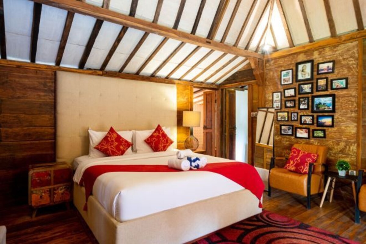 A bedroom with a large bed, wooden walls, and a ceiling with wooden beams.