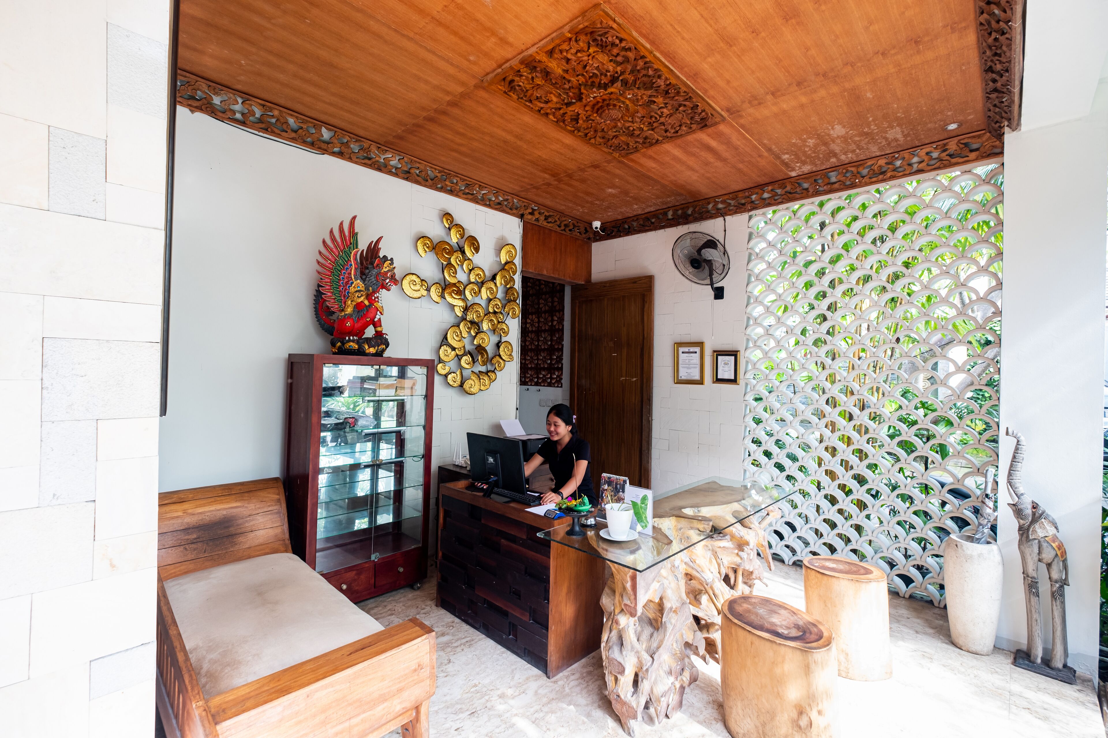 Un área de recepción con un escritorio de madera, una computadora y un elemento decorativo en la pared.