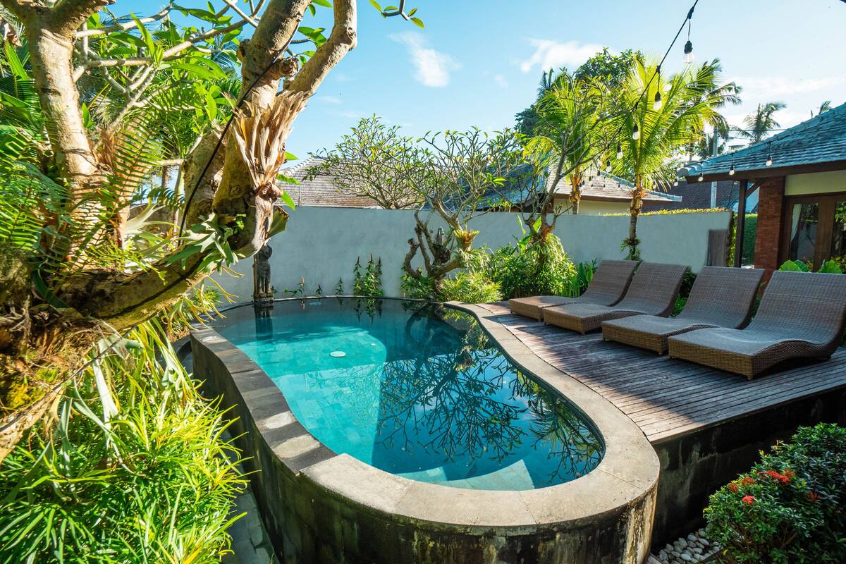 A swimming pool with a wooden deck and lounge chairs.