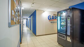 Un couloir d’hôtel avec un distributeur automatique, un panneau d’affichage et une pancarte sur laquelle on peut lire : « Bienvenue chez GAR Host ».
