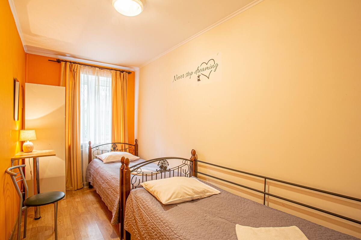 A bedroom with two beds, a desk, and a chair.