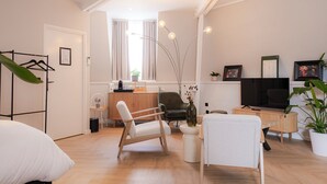 Un salon moderne comprenant un canapé, des fauteuils, une table basse, un téléviseur et un meuble en bois.