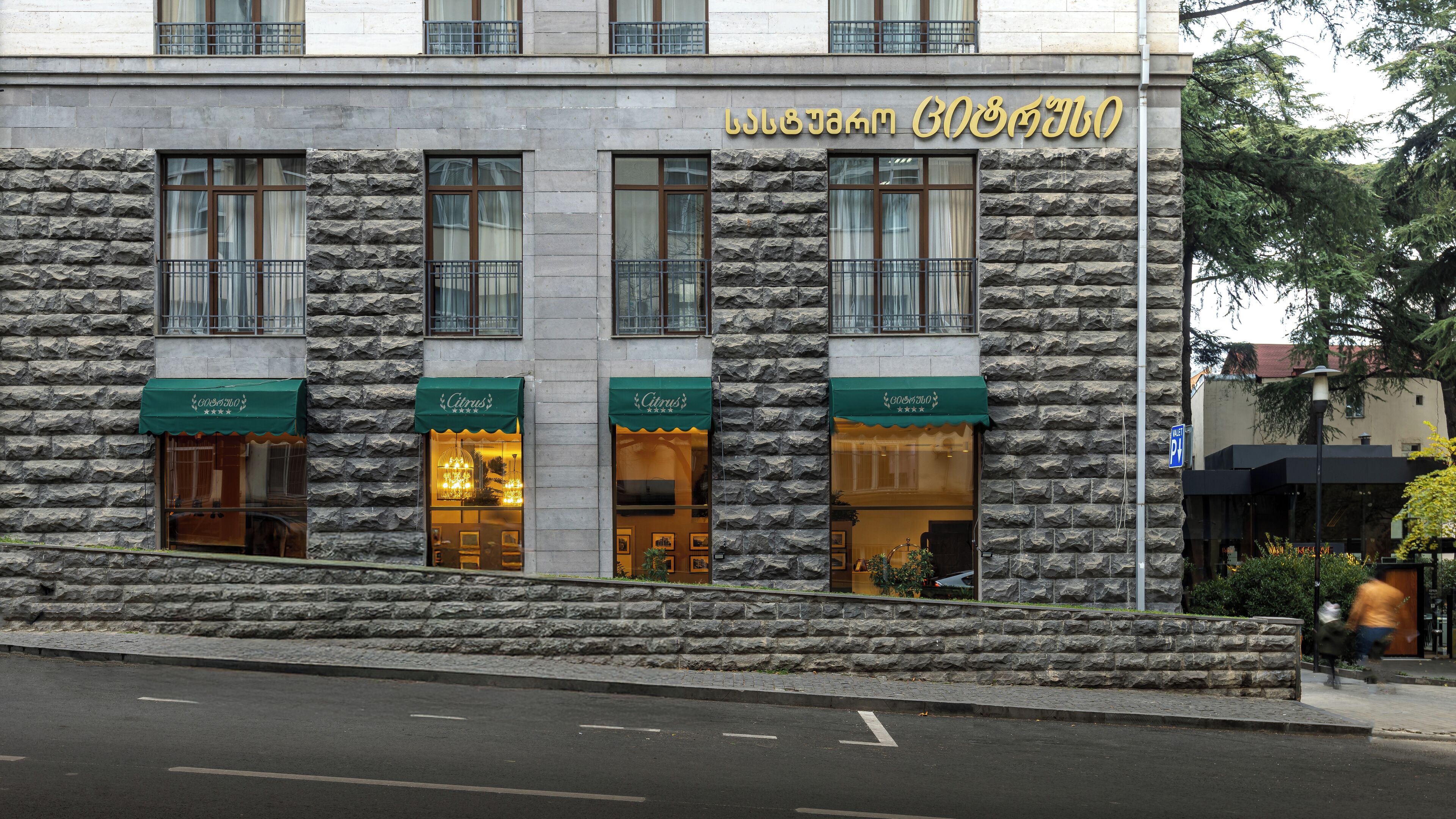 Un edificio con fachada de piedra, varias tiendas y un letrero en un alfabeto extranjero.