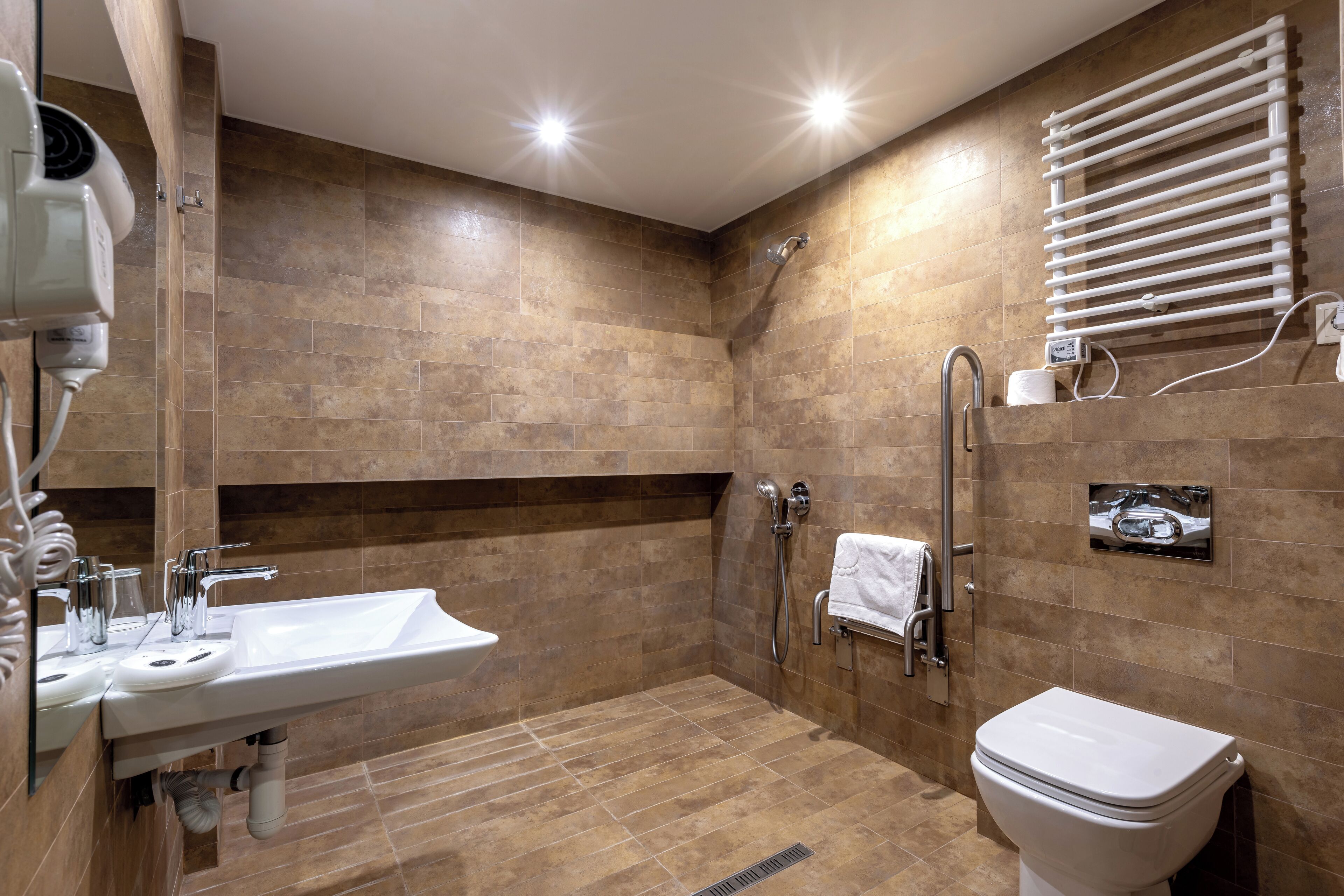 Ein modernes Badezimmer mit einem großen Waschbecken, einer Toilette, einer Dusche und einem Handtuchhalter.