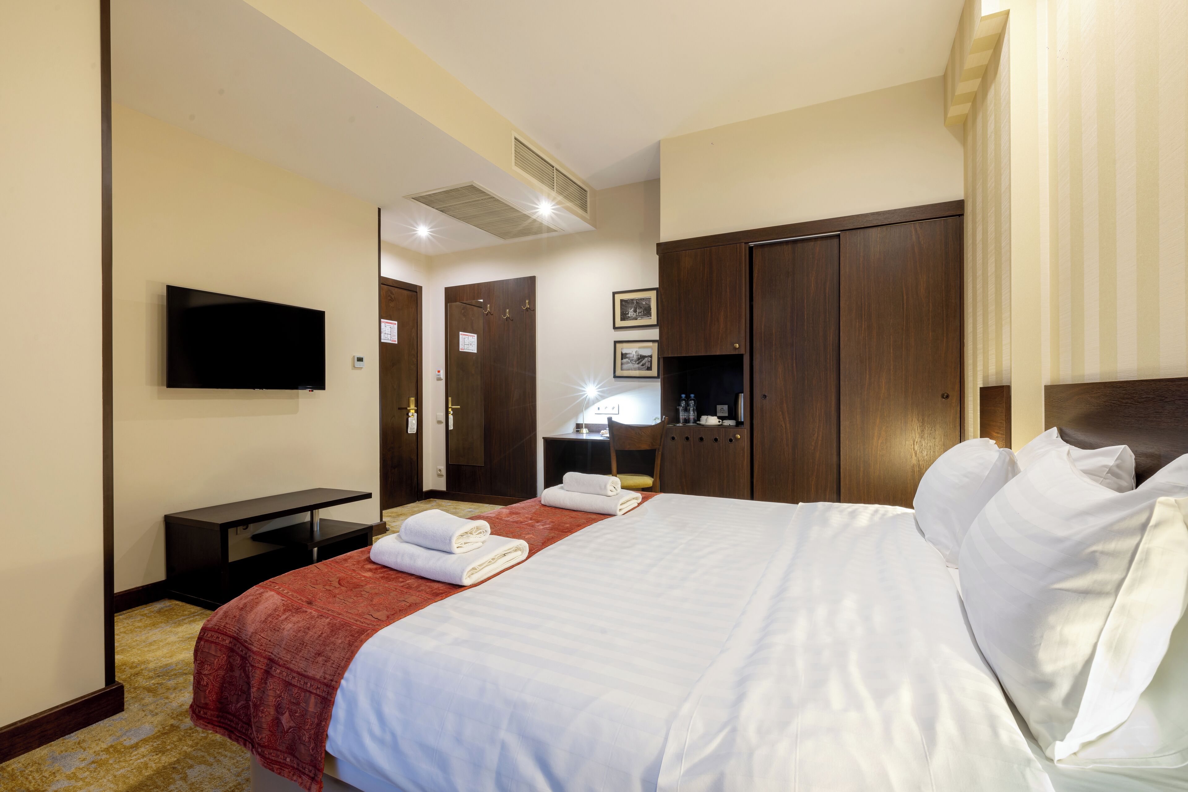 Een hotelkamer met een bed, een televisie, een bureau en een kledingkast.