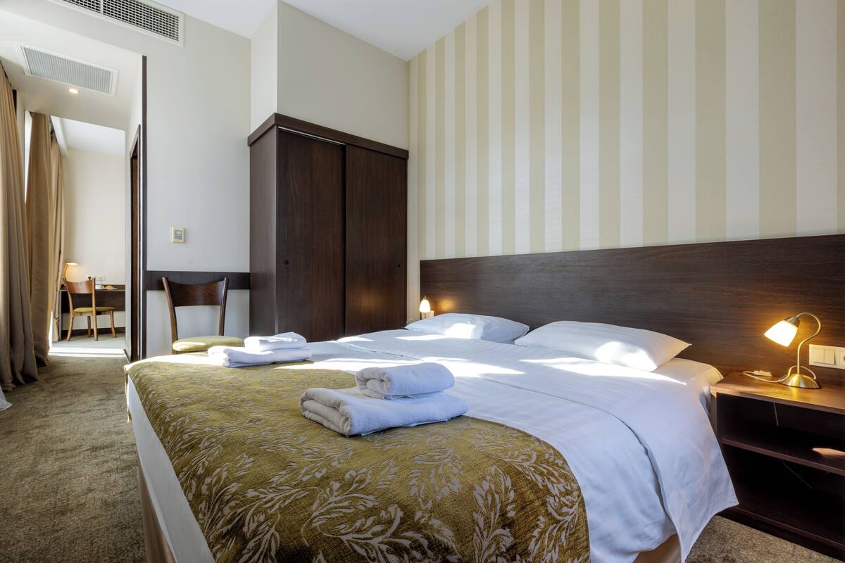 Una habitación de hotel con una cama grande, un escritorio y un armario.