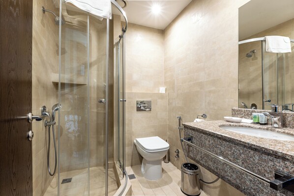 A modern bathroom with a glass-enclosed shower, a toilet, and a granite countertop with a sink and vanity. - Hotel Citrus (Tbilisi)