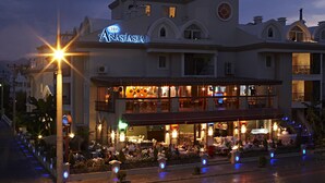 A hotel with a prominent sign, outdoor seating area, and multiple balconies. - Club Anastasia Hotel (Marmaris)
