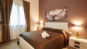 Una habitación de hotel con cama, mesita de noche, lámpara y un cuadro en la pared.