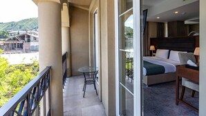 Un balcón de hotel con una cama, una mesa y una silla.