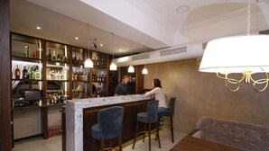 Zona de bar con mostrador de mármol, taburetes azules y un sofá.