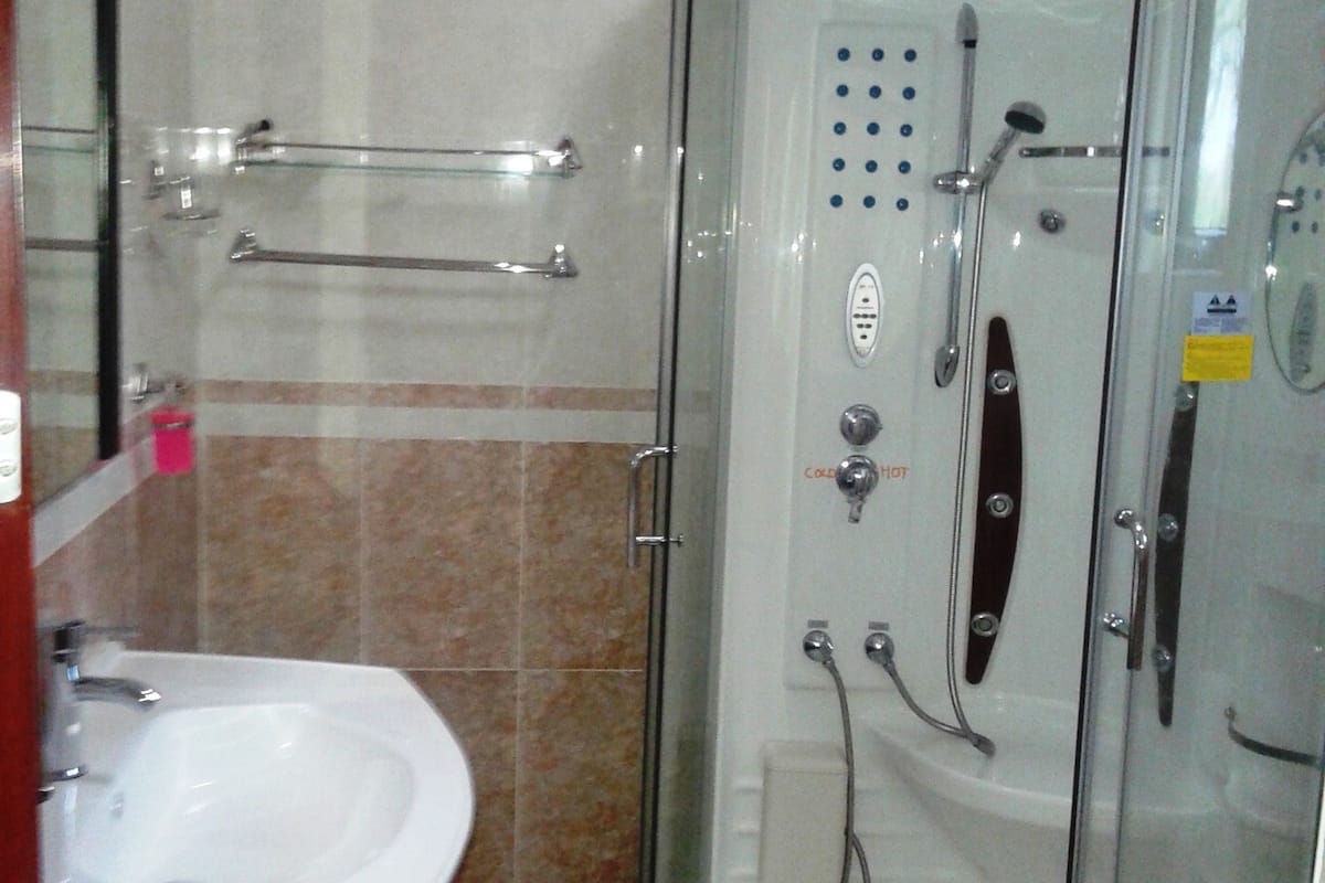 Un baño con ducha envuelta en vidrio, un lavabo blanco y un espejo.