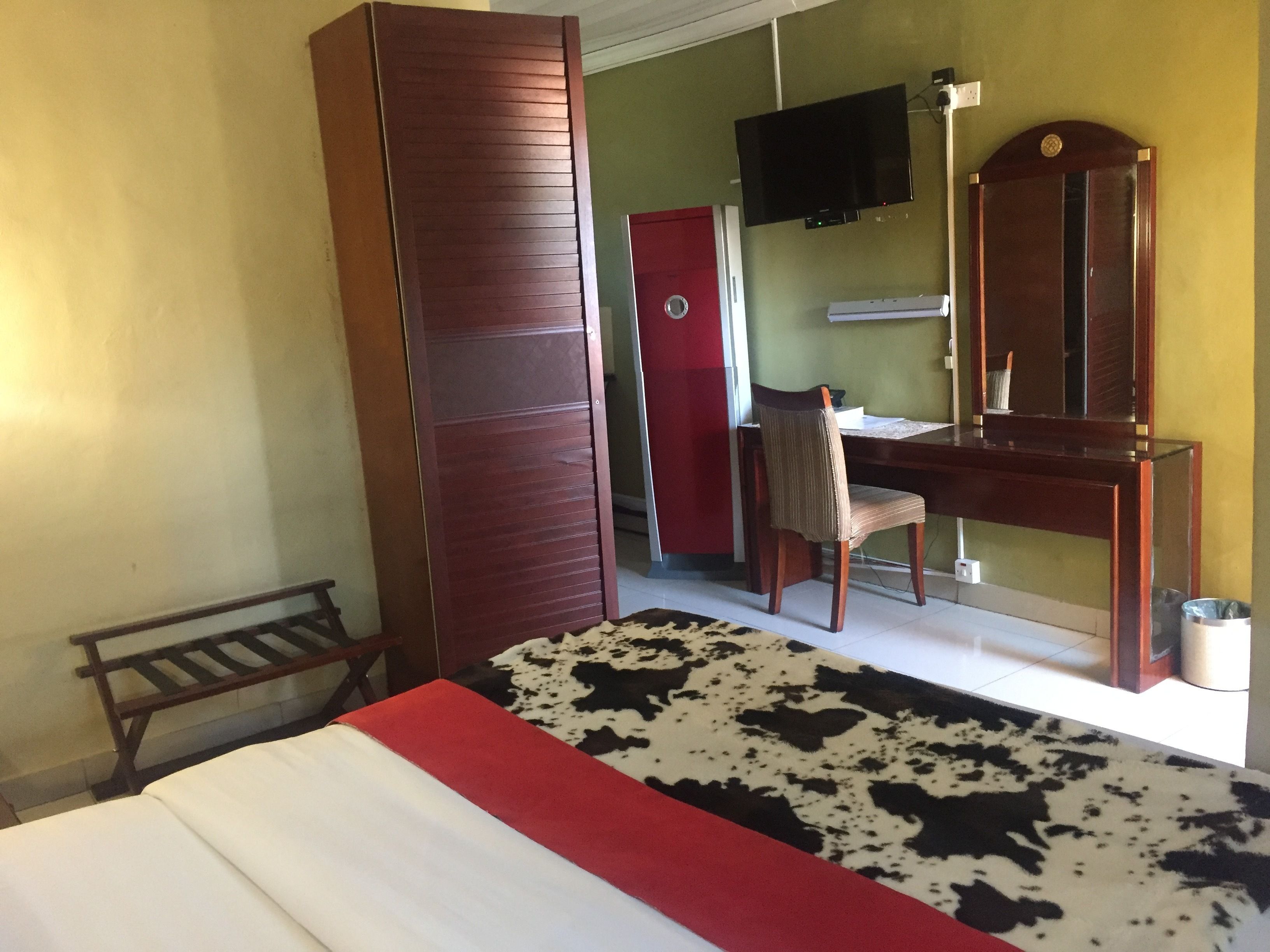 A hotel room with a bed, a desk, a chair, a television, and a wardrobe.