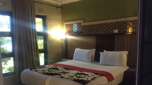 Habitación de hotel con una cama grande, un cabecero con diseño geométrico y vistas por la ventana.