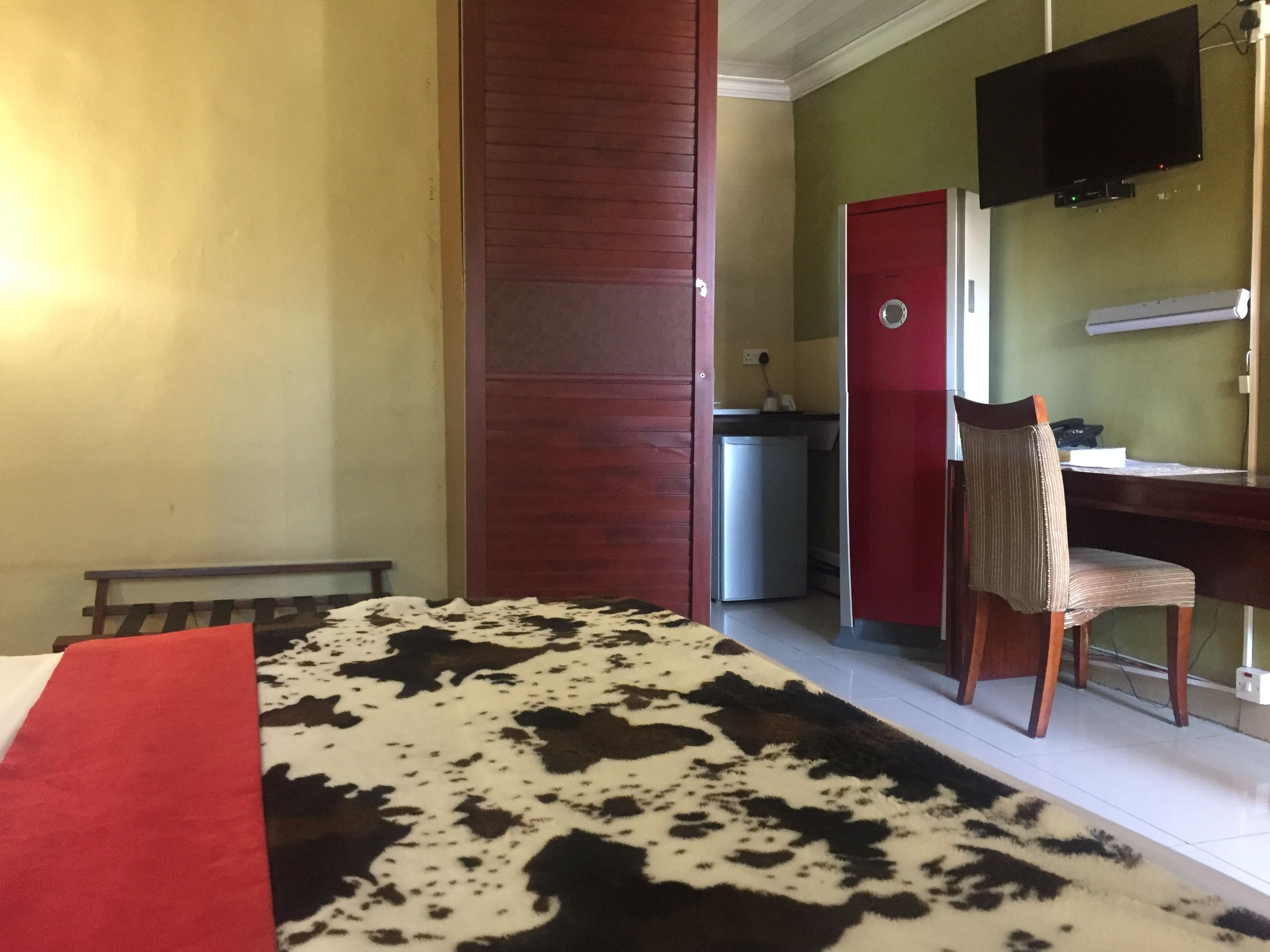 Une chambre comprenant un lit, un bureau avec une chaise, une télévision et un petit réfrigérateur.